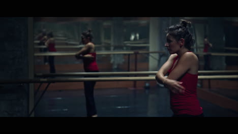 a young woman practices modern dancing and ballet in a moody room full of mirrors