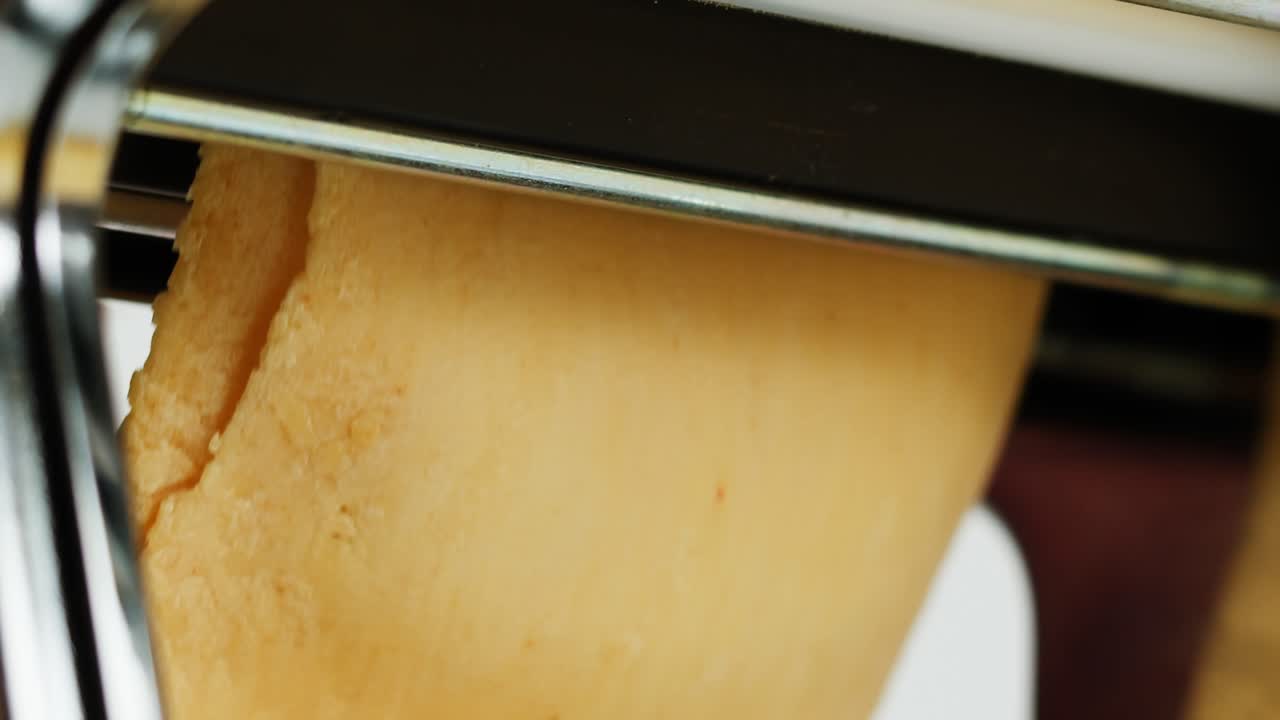 Fresh Pasta Dough Being Flattened by a Manual Pasta Machine