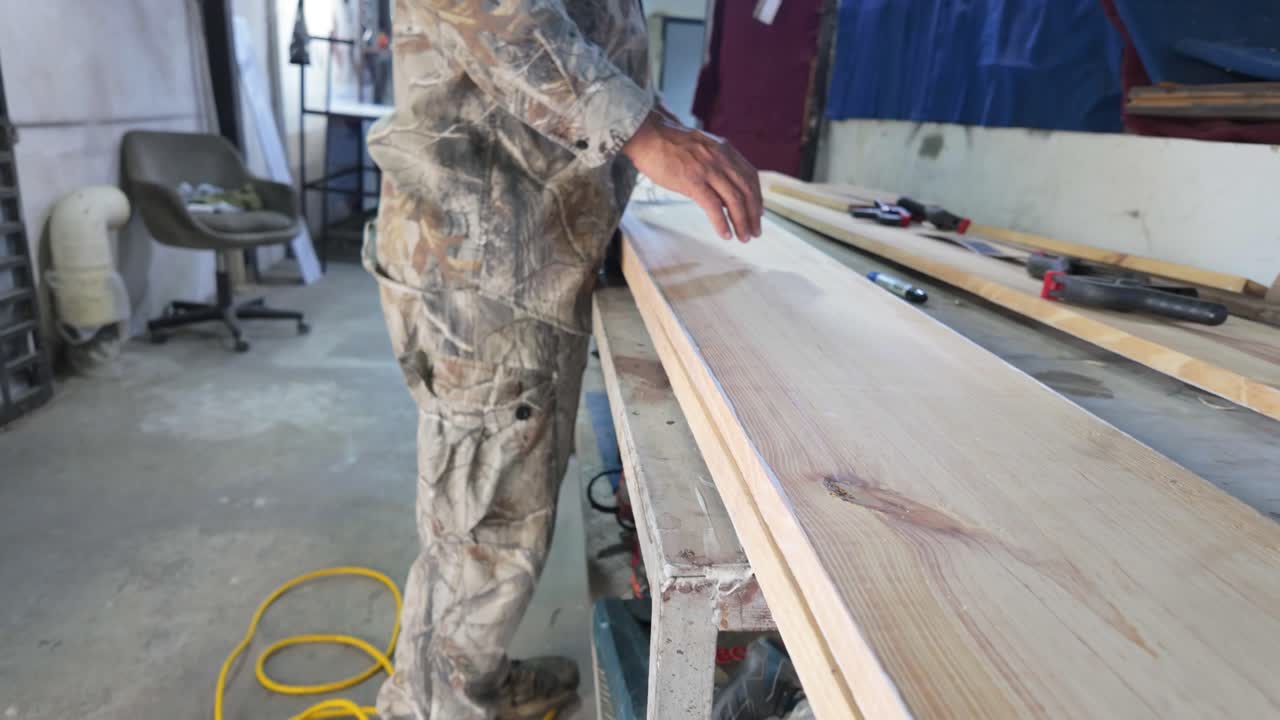 carpintería. Persona trabajando en una tabla de madera larga en un taller rústico