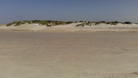 vuelo bajo sobre la playa hacia las dunas de arena y pastizales