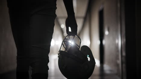 silhouette of athlete with football helmet in a hallway