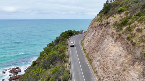 aerial view of a car driving along a winding coastal road in lorne, australia, with stunning ocean views