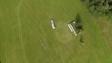 tractor stacking up hay rolls in a field