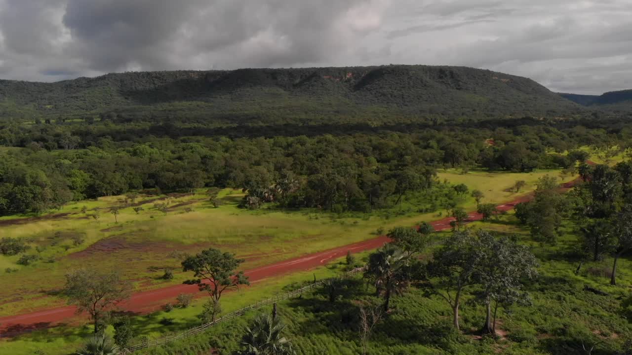 항공 보기, 야생 도로에서 4x4 운전, 녹색 풍경, 배경의 산, 구름, 드론 샷