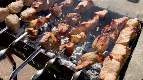 a woman roasts a barbecue on the grill. cooking meat over an open fire. weekend in the country. concept of summer and picnics. toasted pieces of meat, flames in the smoke. turns the skewers with meat