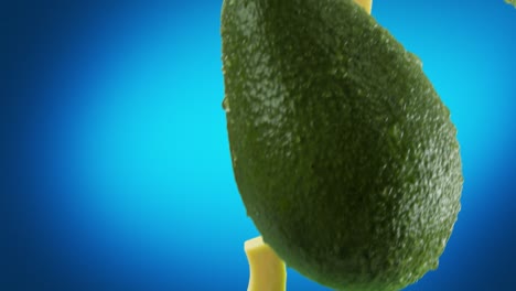 aguacate con rebanadas que caen sobre un fondo azul