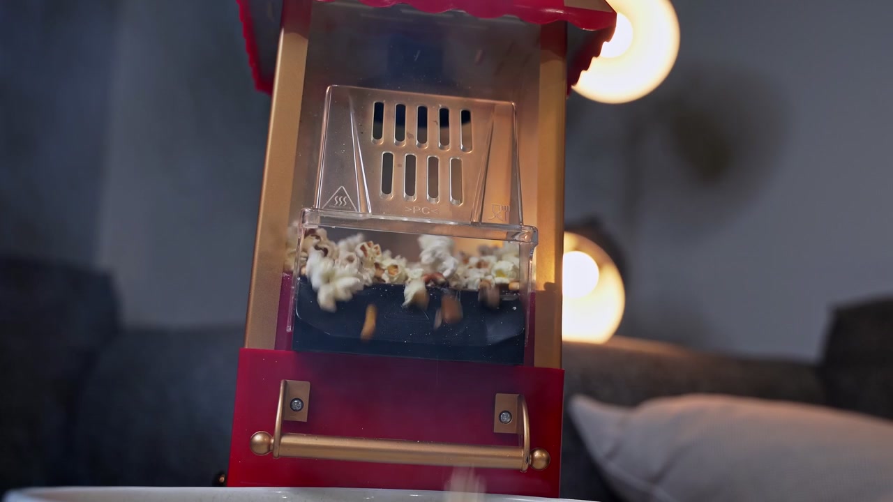 Vintage punainen popcorn-kone poksauttamassa tuoreita maissinjyviä viihtyisässä olohuoneessa pehmeällä bokeh-valaistuksella. Ihanteellinen kotiviihteeseen ja elokuvailtojen lifestyle-sisältöön.
