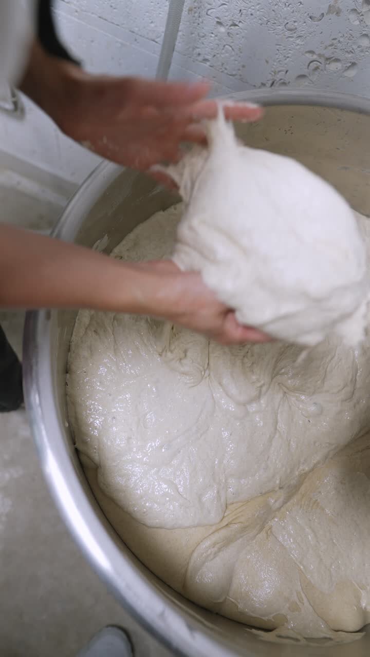 Woman kneading dough in a large metal bowl