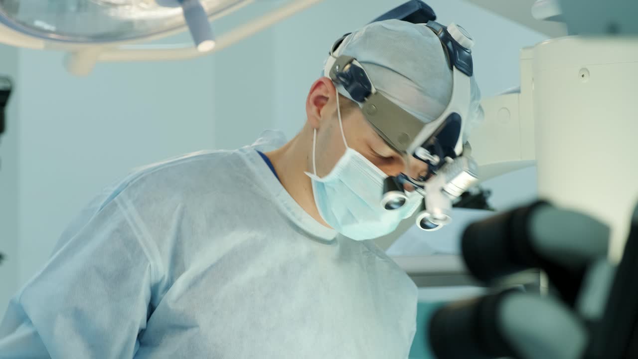 los cirujanos realizan una operación y miran a través de un microscopio