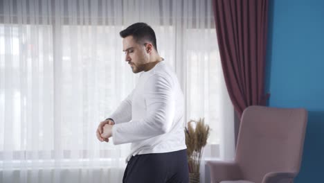 Young-athletic-man-exercising-at-home-to-stretch-and-warm-up-his-waist-and-back.