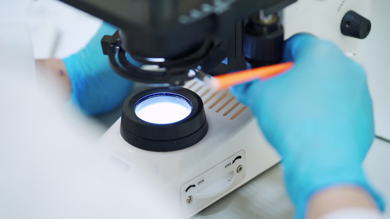 Chemist examining blood with microscope. Close up shot of scientific laboratory microscope examining blood