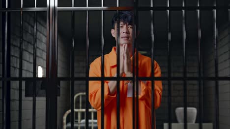 asian male prisoner in handcuffs standing in prison, making pray hand gesture asking for something