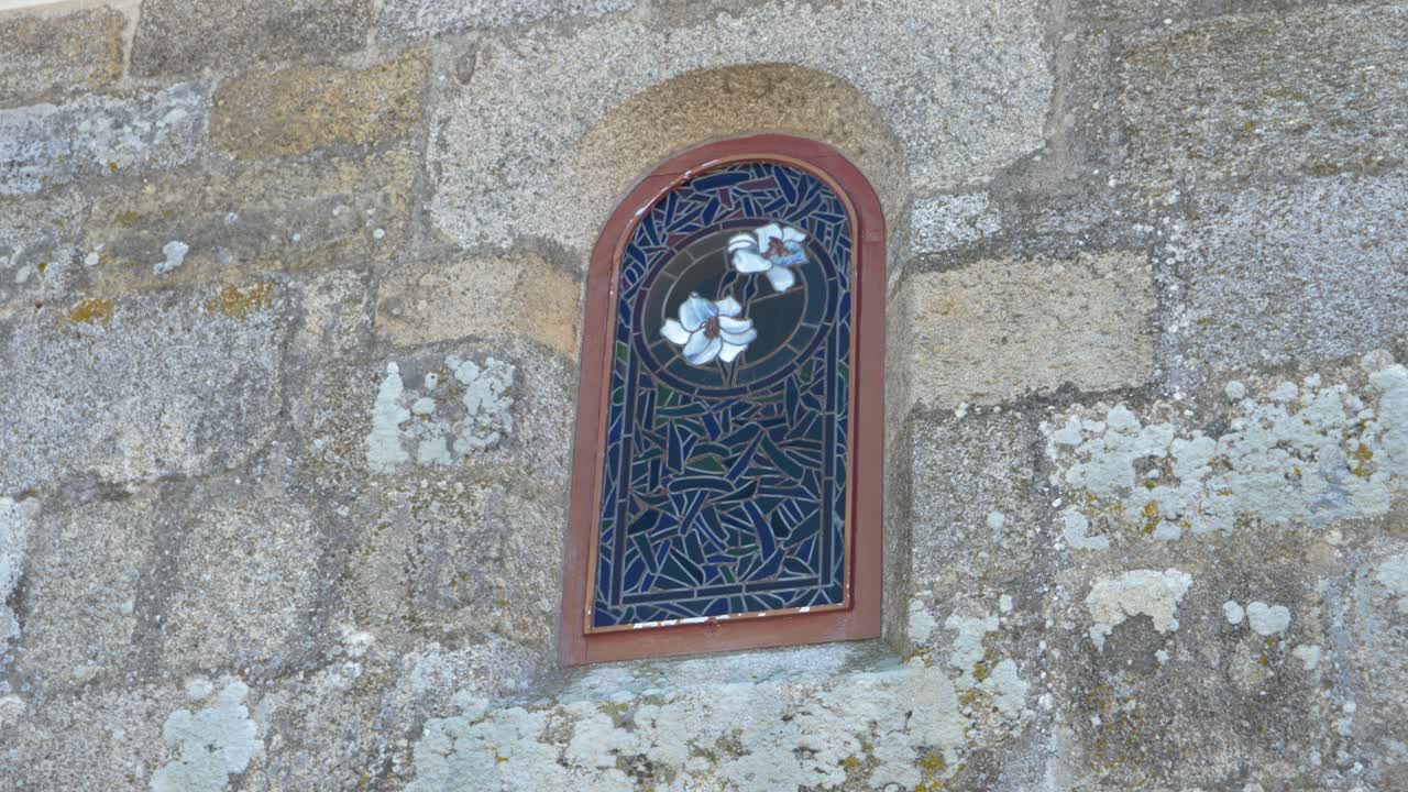 Stained Glass Window in Stone Wall with White Flowers