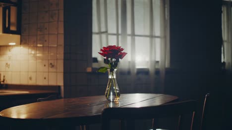 red roses arranged in a glass vase on a rustic wooden table enhance the romantic ambiance of a vintage kitchen, beautifully illuminated by soft natural light streaming through the window