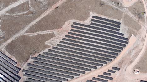 Vista-Superior-De-Drones-Paneles-De-Fila-Del-Parque-De-Energía-Solar-Fotovoltaica-En-Las-Colinas-Día-Soleado