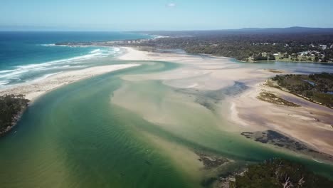 aerial footage of the mouth of the wallagaraugh river at low tide with mallacoota in the background, victoria, australia, december 2020