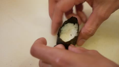 Hand-Press-on-Japanese-Rice-Wrap-with-Dry-Seaweed,-Making-Sushi,-Close-Up-1
