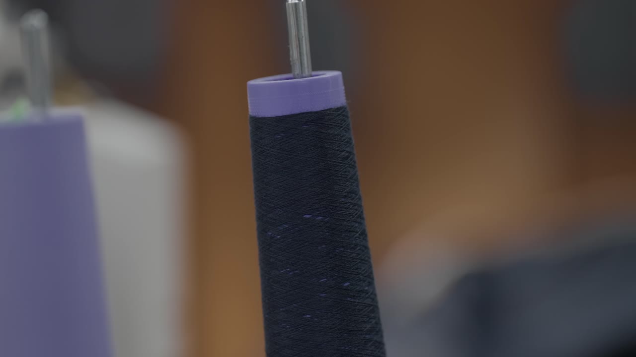 Rocchetto di filo blu scuro su perno di macchina da cucire industriale in fabbrica