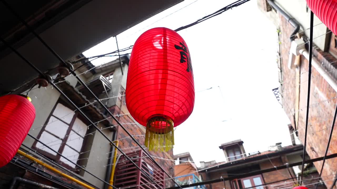 Low angle orbit around a red lantern tied with yellow bows hanging from a corridor roof in Tianzifang. Shanghai, China