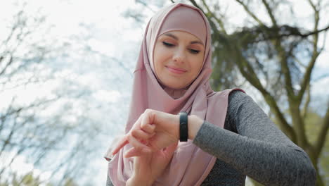 woman in hijab checking smartwatch outdoors