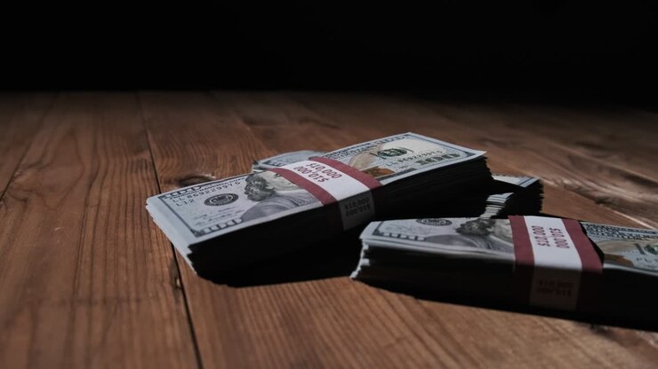 Three Stacks of 10000 American Dollars Banknotes in Bundles Lie on Wooden Table