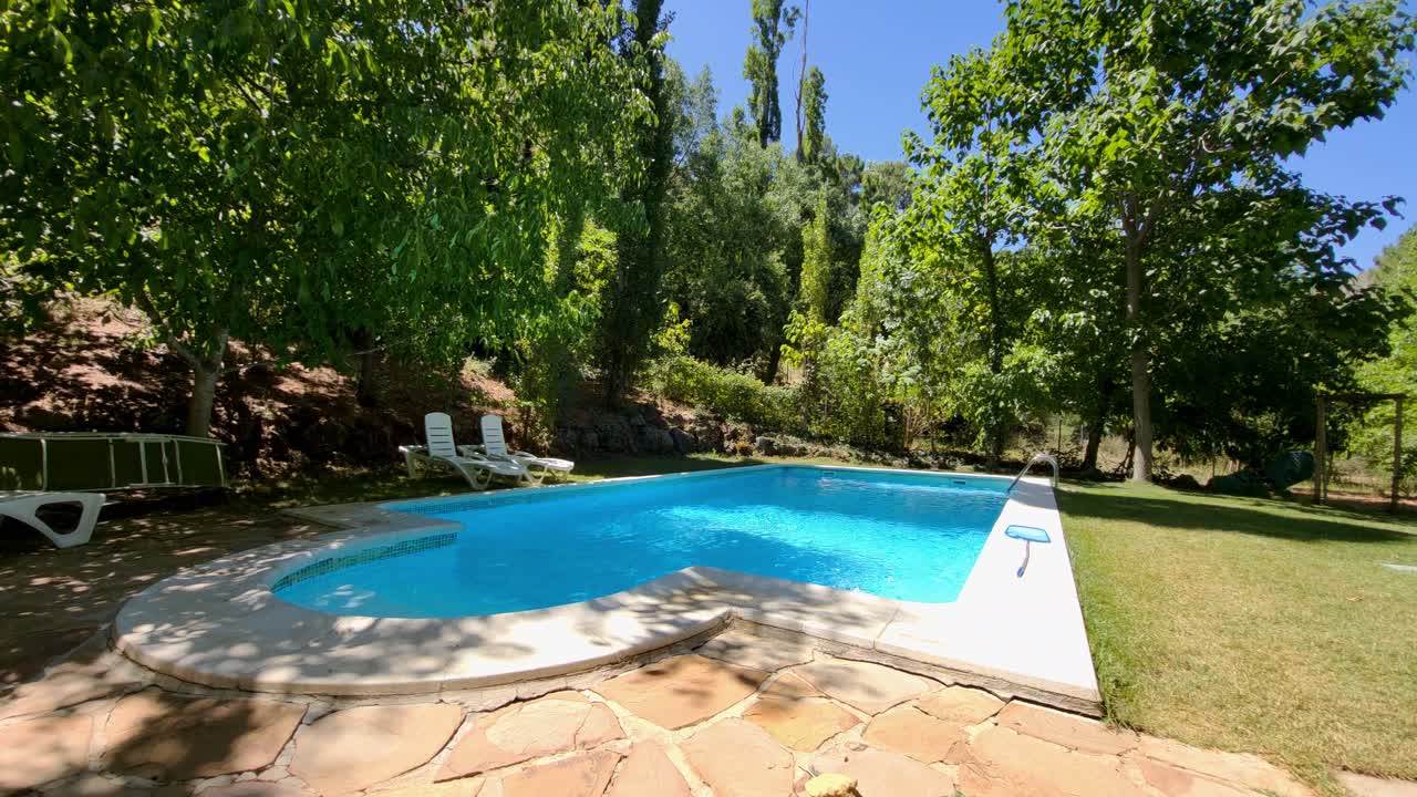 Farverig blå pool ved siden af skoven og græsområdet. Sommerferie. Pool mellem træerne. Spanien