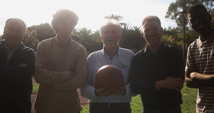 Happy Multi-Generational Men Smiling with a Football in Sunny Park