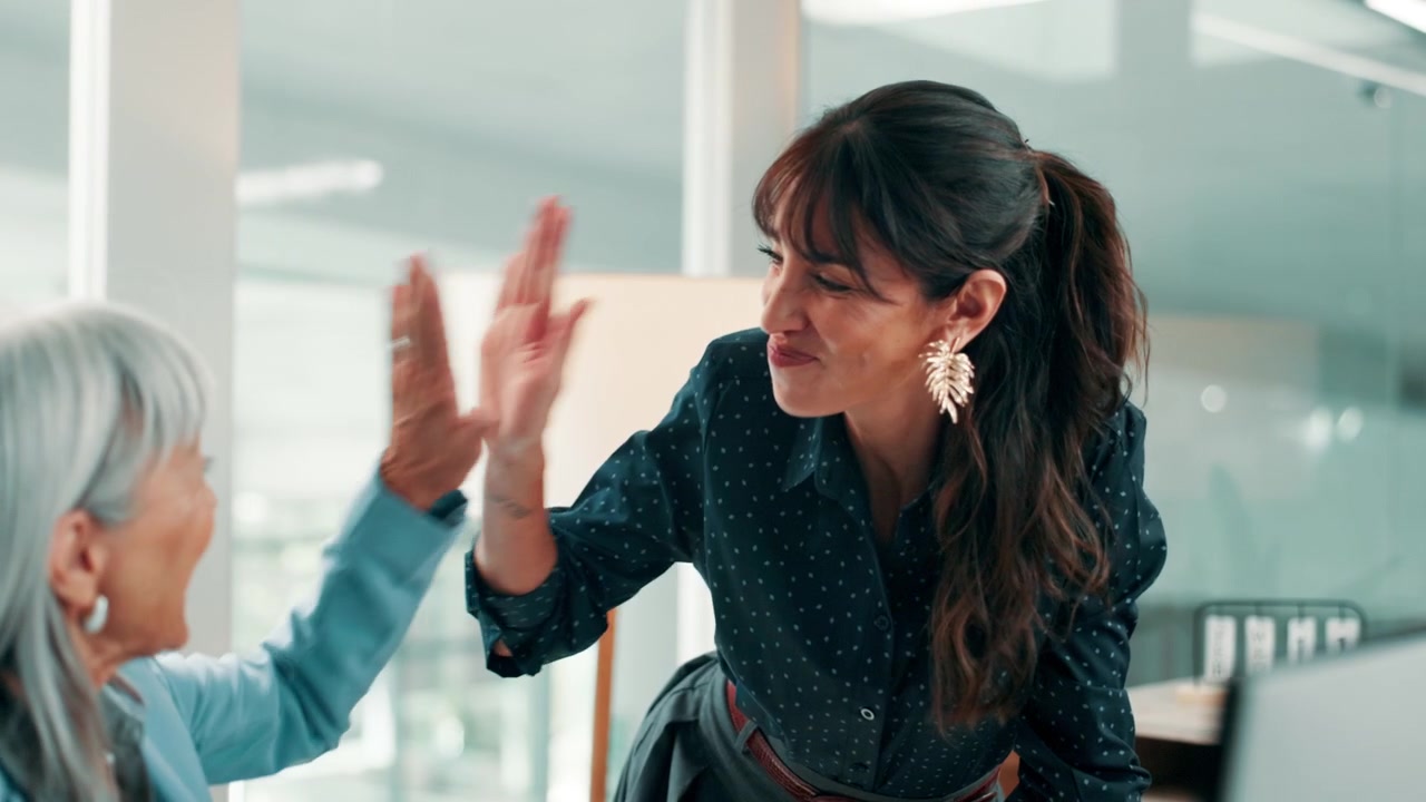 Two Businesswomen Celebrating Success with a High Five in Modern Office