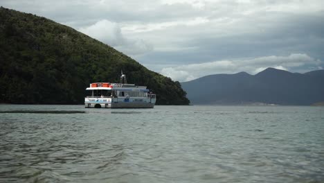 pelorus mail boat in marlborough sounds, new zealand with green hills in background