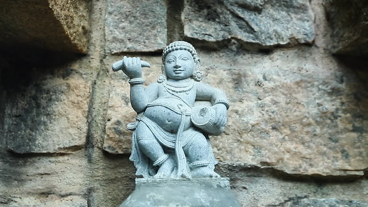 Carving of an Asian man with a musical percussion instrument. Handheld, close up