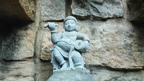 carving of an asian man with a musical percussion instrument. handheld, close up