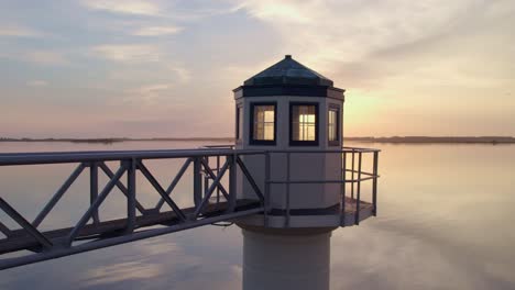 sun appears behind oostmahorn lighthouse friesland during sunrise, aerial