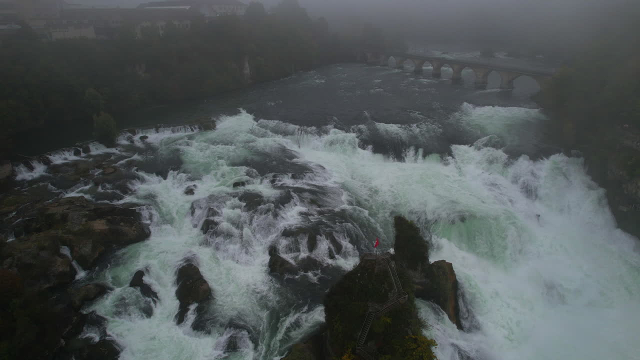 Rhine Falls cascading water and medieval Laufen Castle on a foggy day in Schaffhausen, Switzerland