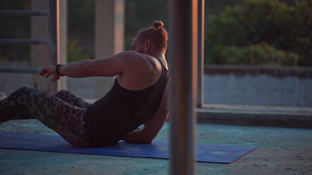 Uomo che esegue esercizi per il core su un tappetino da yoga al tramonto.