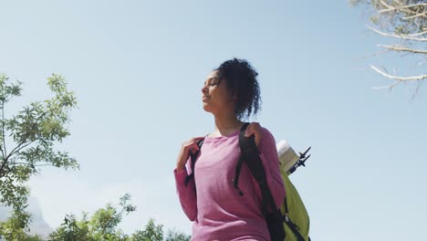 Smiling-biracial-woman-looking-away-and-hiking-in-countryside