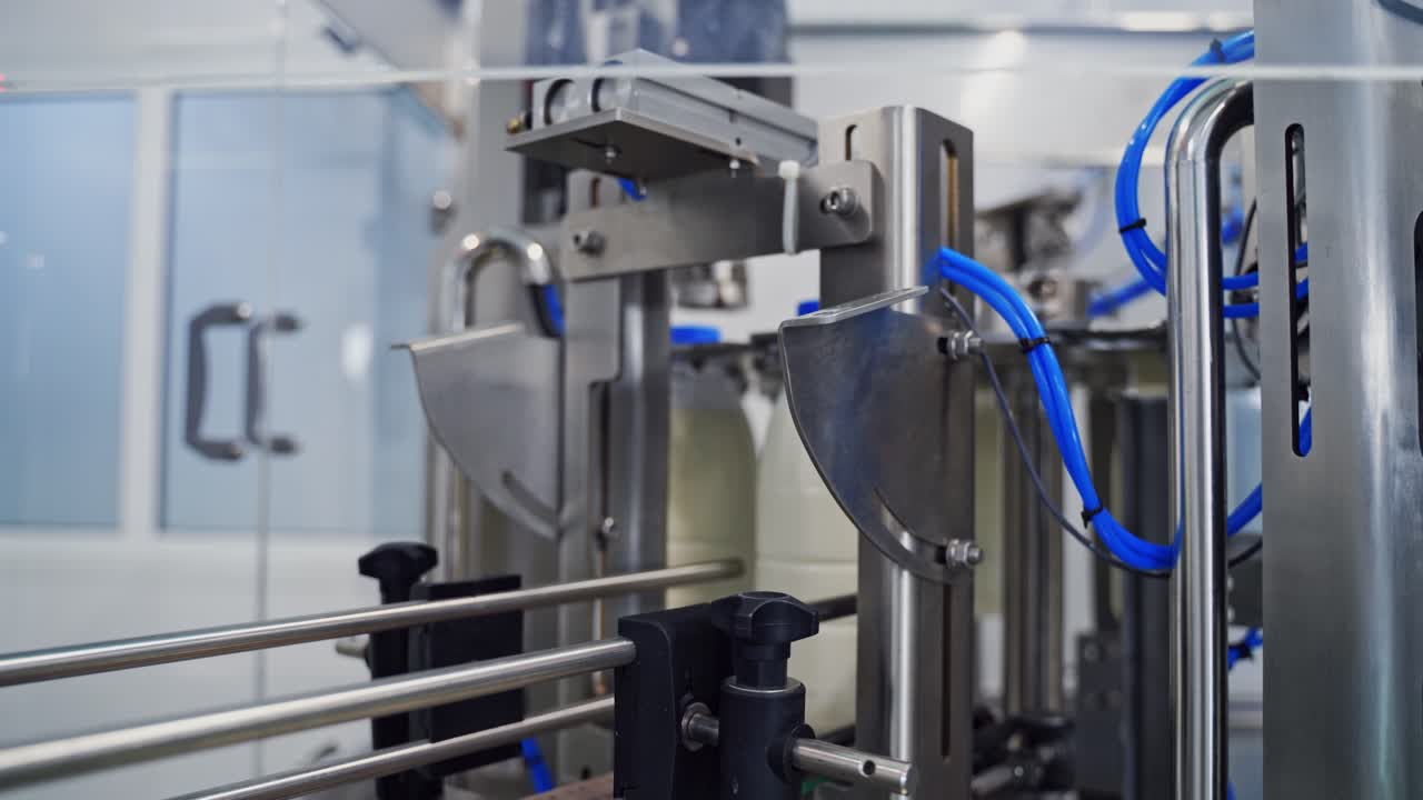 Dairy industry in the robotic plant indoors. Bottles with milk moving on a conveyor line. Modern technology of producing dairy products.