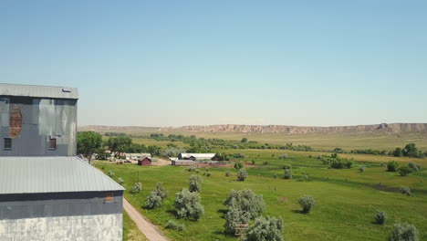 Aerial-fly-past-grain-tower,-farmland,-and-train-tracks-in-central-Wyoming