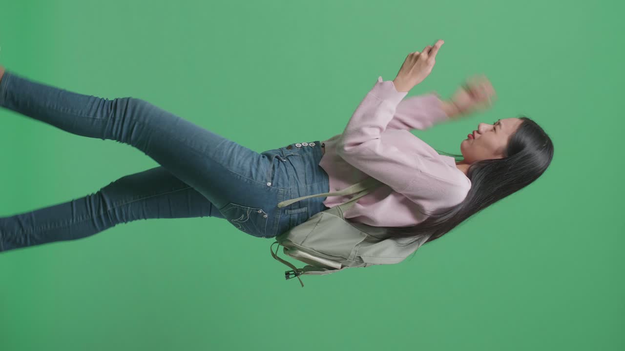 화가 난 아시아 여성 학생이 모바일 게임을 하고 녹색 스크린 스튜디오에서 는 동안 패배합니다.