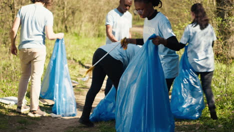 african american girl picking up trash with a long claw and garbage bags