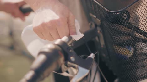 a bike handlebar with a basket being cleaned with a white sheet by a bike mechanic