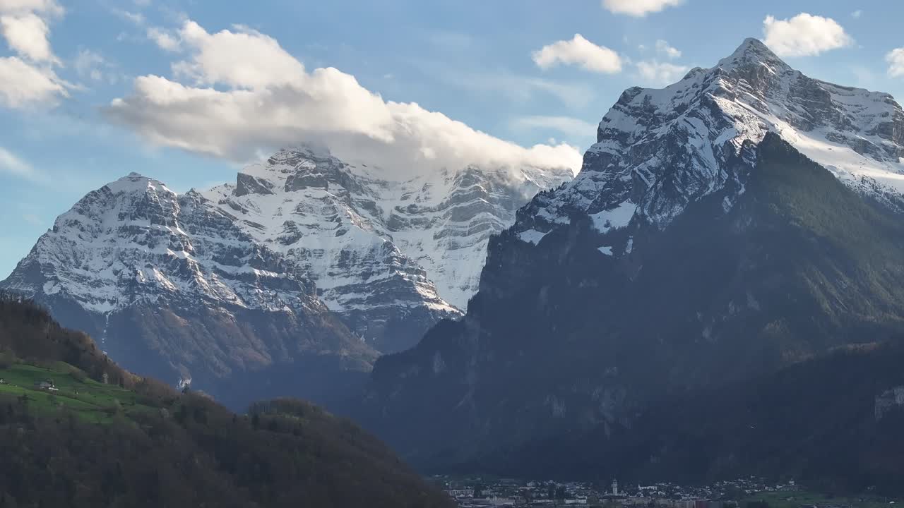 majestuosa vista aérea de vorder glärnisch, wiggis y rautispitz en glarus nord, suiza, que se eleva sobre un pintoresco pueblo