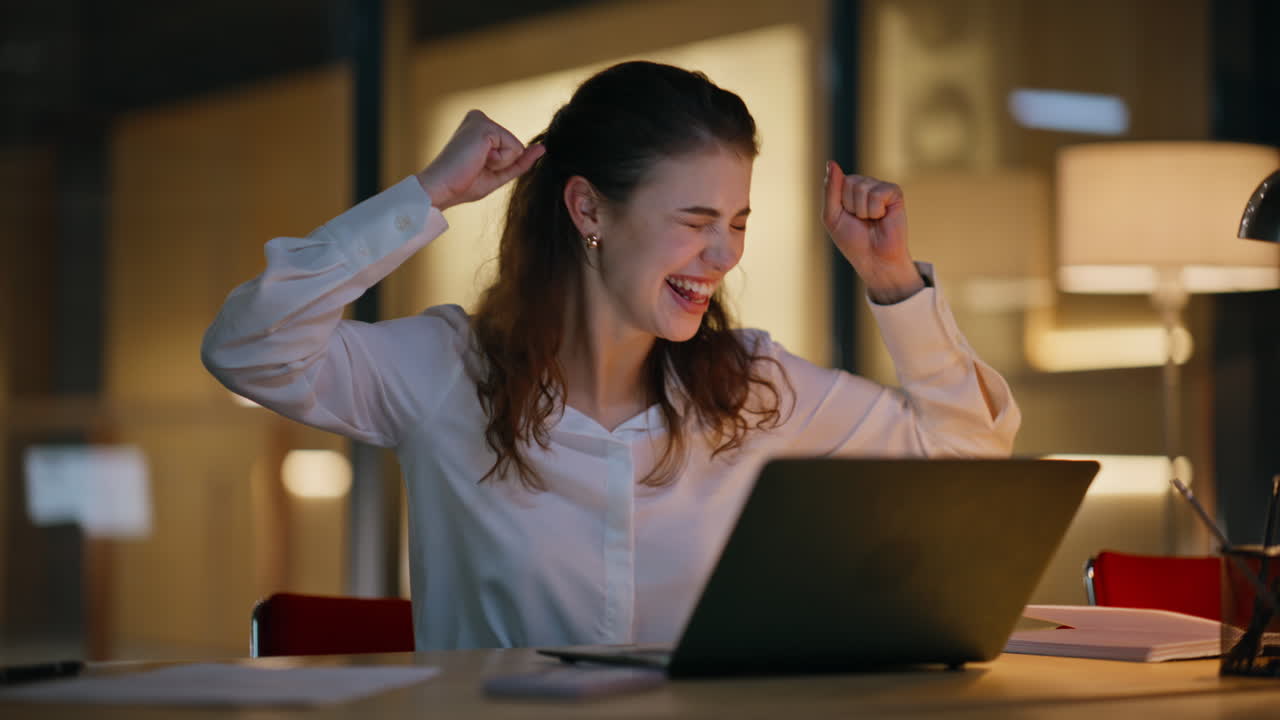 Excited business woman rejoicing online win sitting night office center closeup