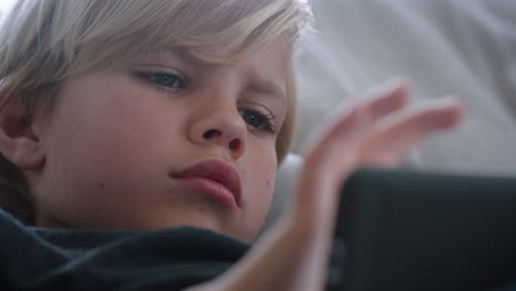 happy little boy using smartphone playing game relaxing on sofa at home child browsing online with mobile phone technology anti social addiction concept 4k footage