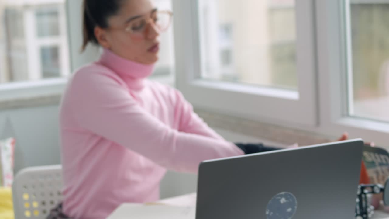 Donna con tutore al polso lavora al computer portatile e beve caffè