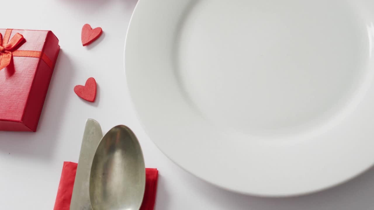 Roses and plate with cutlery on white background at valentine's day