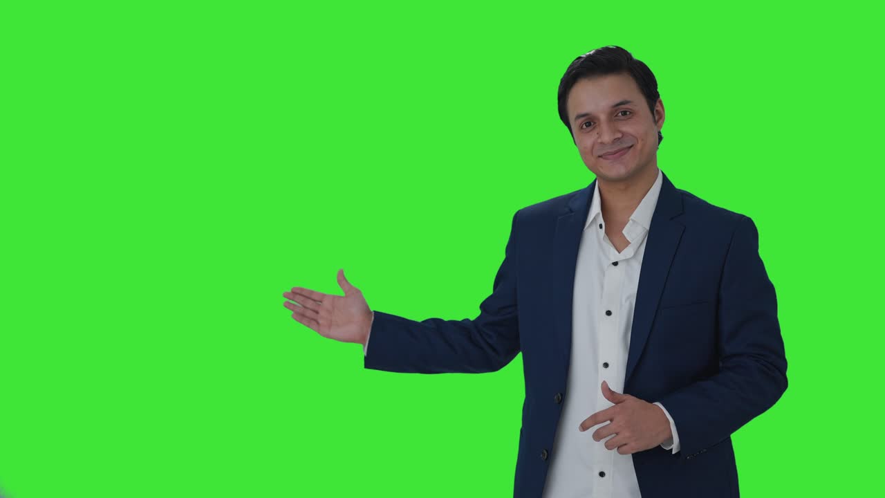 periodista indio feliz señalando el espacio de copia y mostrando los pulgares hacia la pantalla verde