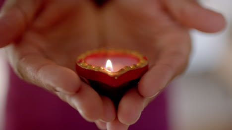 celebrating traditional indian festival of diwali, person holding lit decorative candle