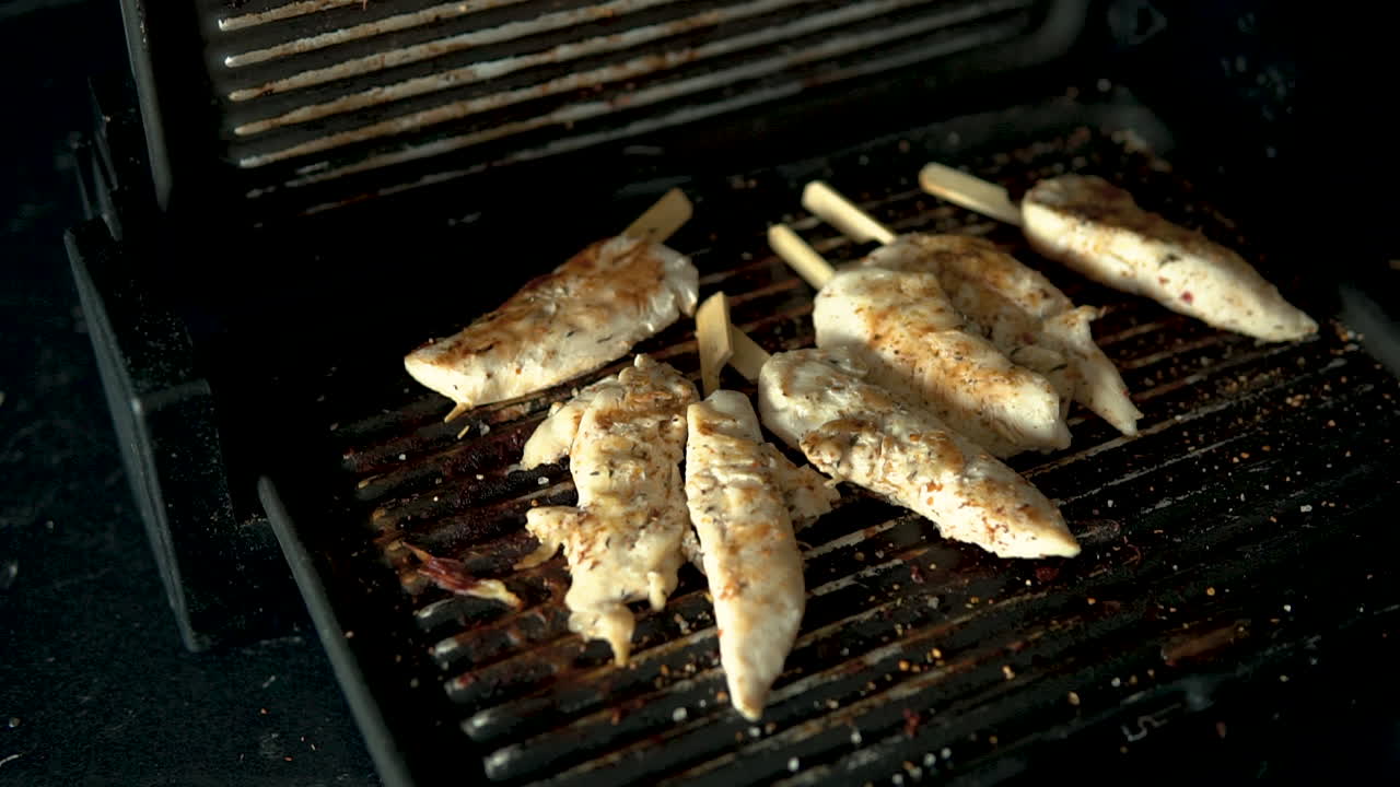 고기를 굽는 석쇠를 슬로우 모션으로 열고, 향신료를 넣은 수제 치킨을 굽고 있어요.