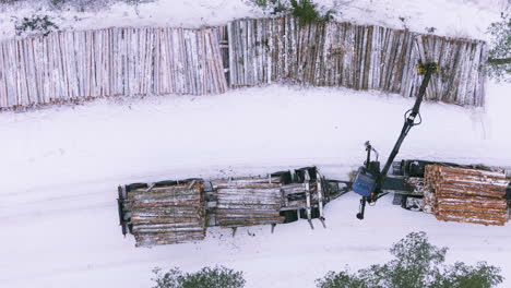 loading of logs from snowy terrain onto truck using grapple loader