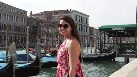 Mujer-Atractiva-Con-Vestido-Estampado-Rojo-Sonriendo-A-La-Cámara-En-Venecia,-Italia